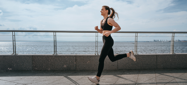 Barna hajú lány fut a tengerparton.