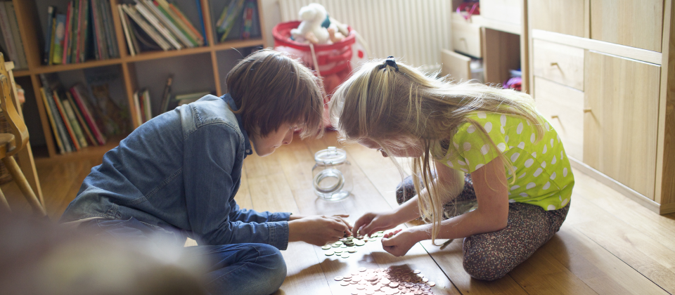 Gyerekek számolgatják a földön ülve a megtakarításukat a szobában.