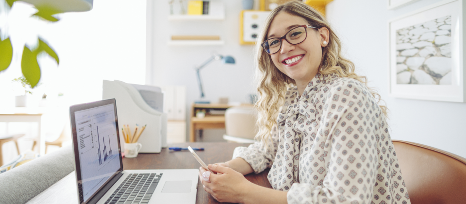 Fiatal mosolygó z-generációs nő a laptopon számolja megtakarításait.