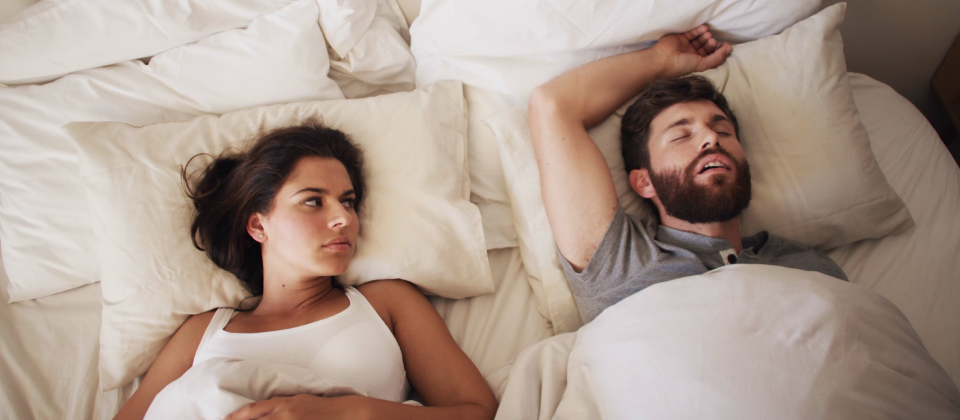 Fiatal pár fekszik az ágyban, a férfi alszik a nő pedig figyeli.
