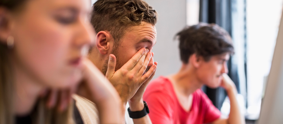 Fiatal férfi álmosan ül a tanteremben.