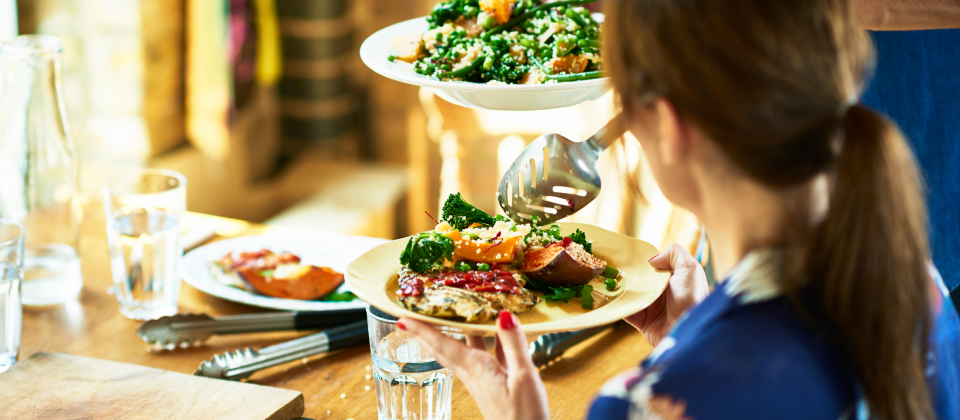 Nő salátát szed az asztalnál.