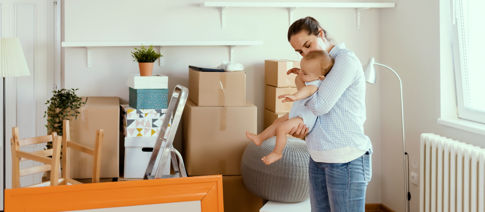 Anyuka kezében tartja a kisbabáját az új lakásukban.
